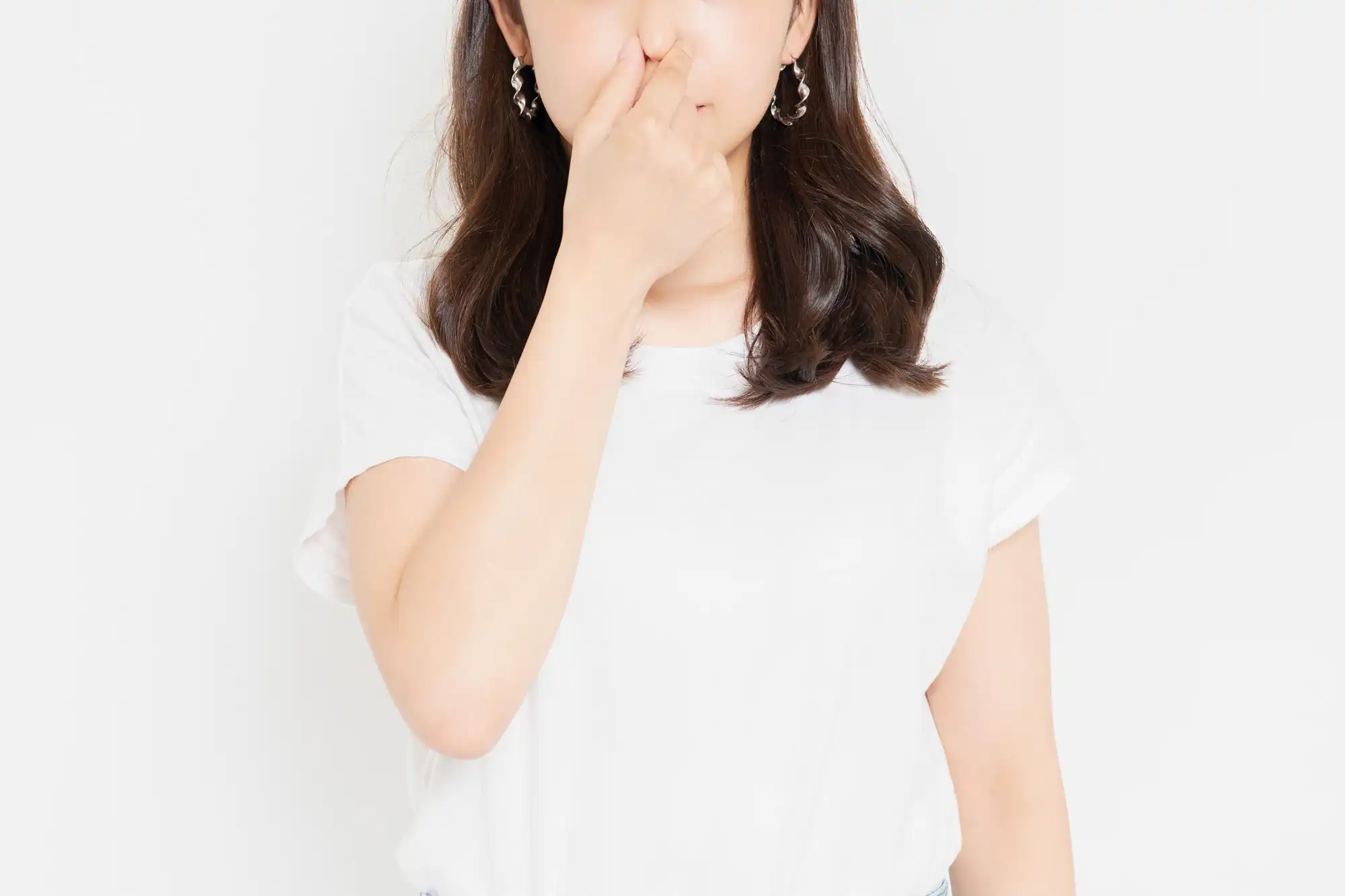 白い服をきた女性が鼻をおさえている