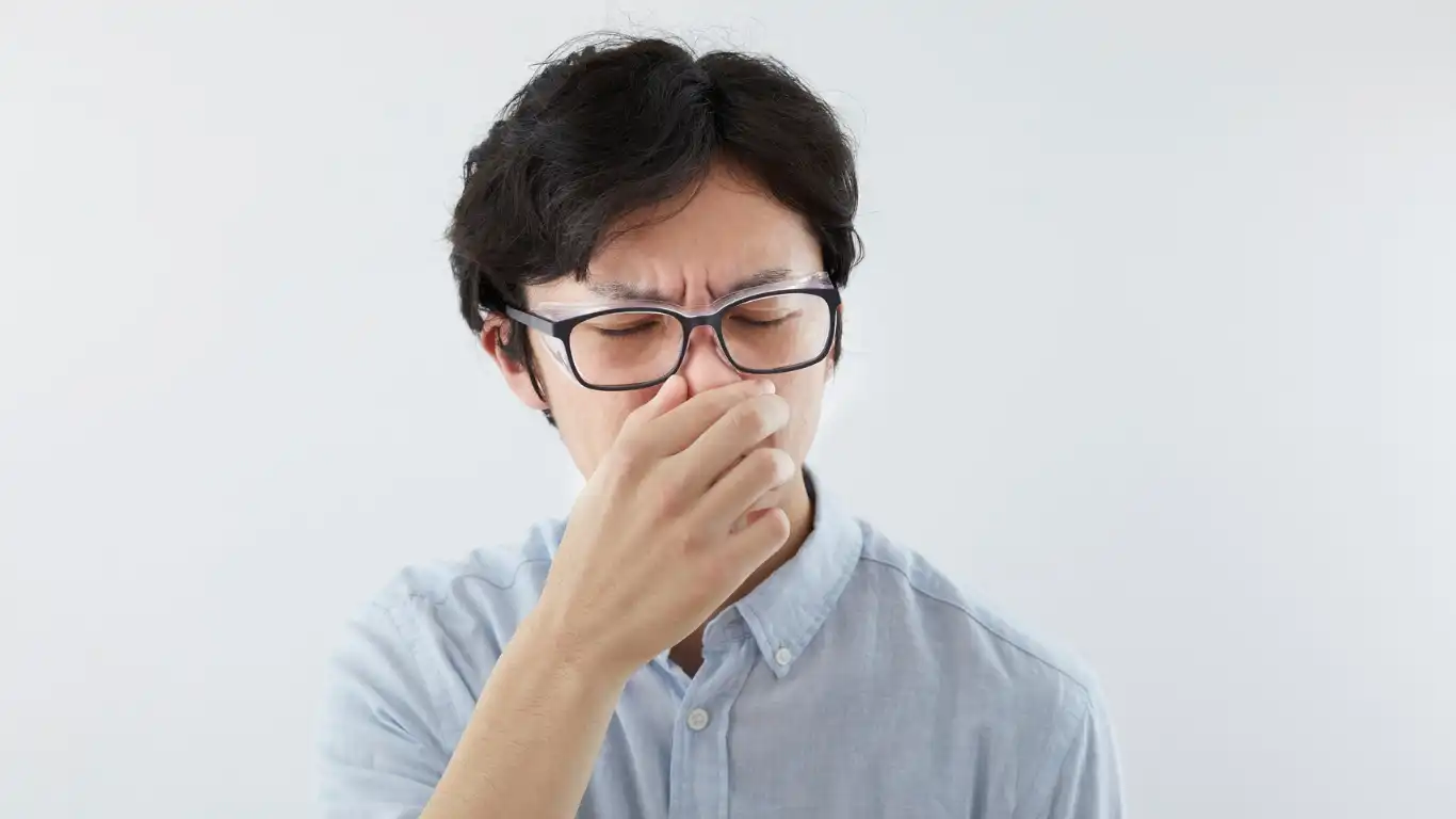 メガネを掛けた男性が臭い匂いで思わず鼻をつまんでいる様子
